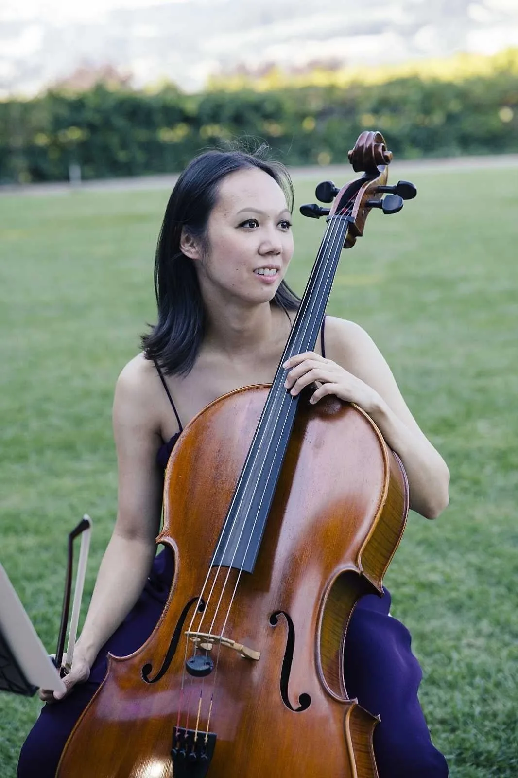Stephanie Wu seated outdoors with her cello