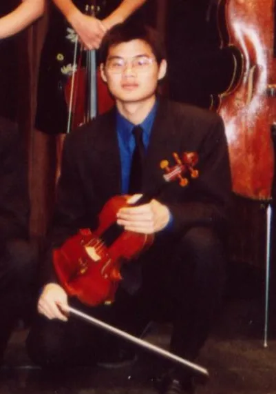 Tyson Mao seated in concert attire holding his instrument and bow